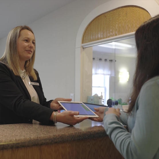 Dental team member at front desk smiling at a patient