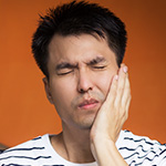 Man in dental pain holding cheek