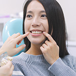 Woman in dental chair pointing to her tooth