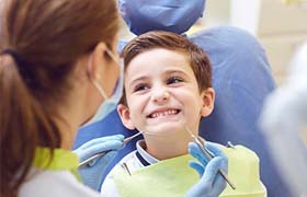 A little boy in the dentist chair ready for a cleaning.