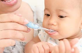 A woman brushing her baby’s teeth.