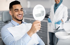 Dental patient using mirror to admire his smile