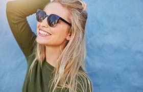 Smiling, healthy woman in sunglasses with no toothache in New Bedford