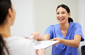 Dental team member handing clipboard to patient