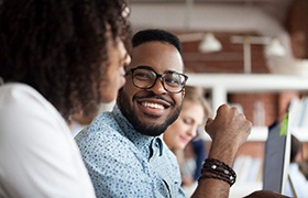 Man in button up shirt smiling at coworker in office