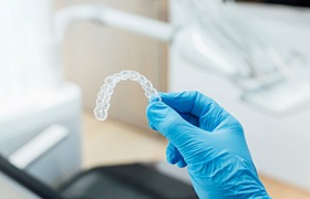 Dentist holding clear aligner with blue gloves