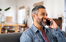 Man smiling while talking on cellphone at home