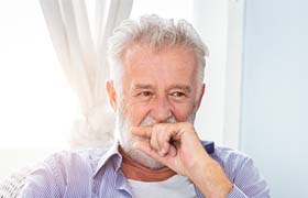 Older man covering his smile