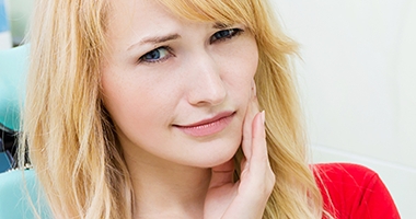 Woman in dental chair holding cheek