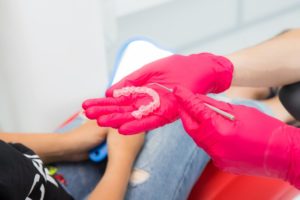 dentist holding a clear aligner in front of patient