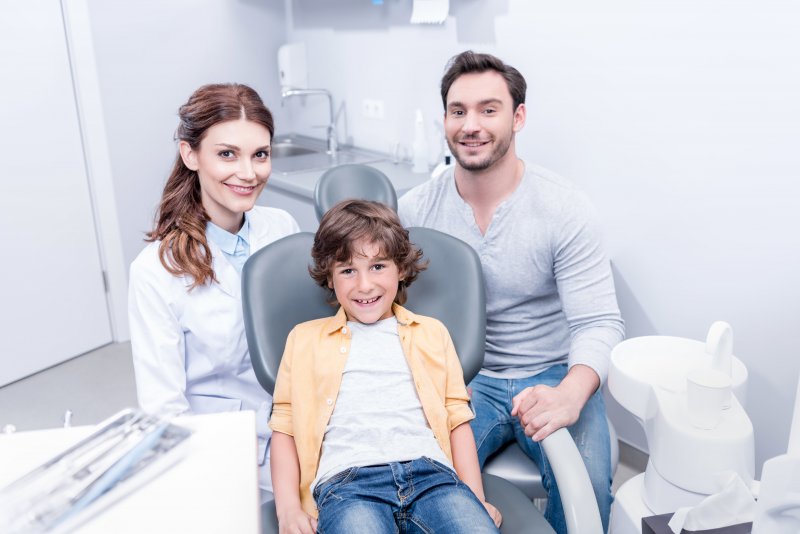 Smiling boy, father, and female dentist at dental office