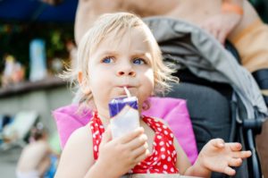 Suspicious little girl with cavities drinking a juice box