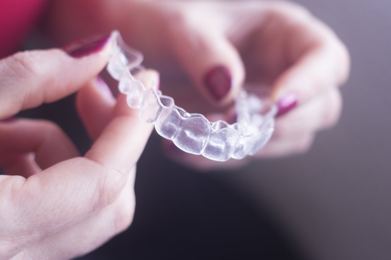 person holding Invisalign aligner