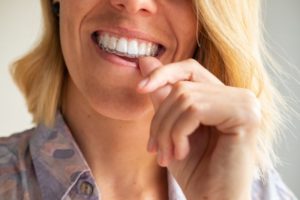 a woman putting mail-in clear aligners into her mouth
