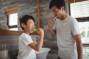 a father and son having fun while brushing their teeth