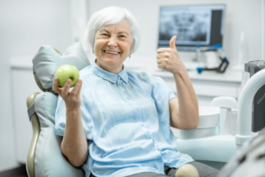 Patient holding an apple and smiling while giving a thumbs up